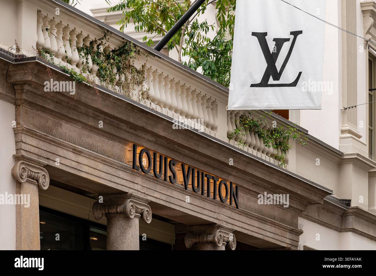 Milano, Lombardia, Italia - 22 aprile 2026: Ingresso al lussuoso negozio Louis Vuitton con il suo nome e l'iconica bandiera monogramma Foto Stock
