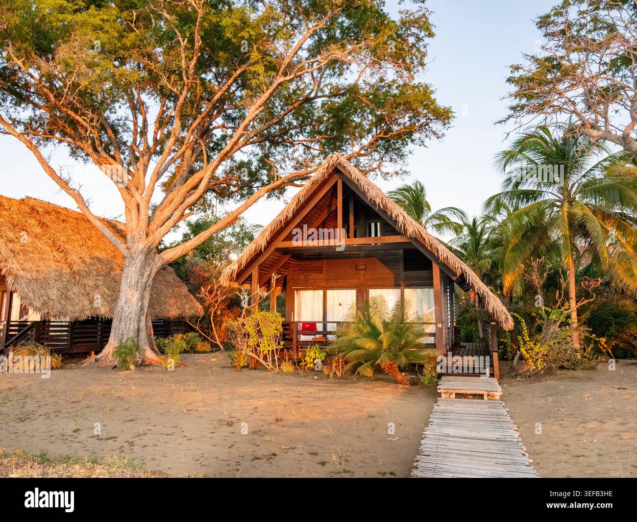 I bungalow per gli ospiti si trovano sulla spiaggia sotto gli alberi della riserva privata Anjajavy in Madagascar durante il tramonto Foto Stock