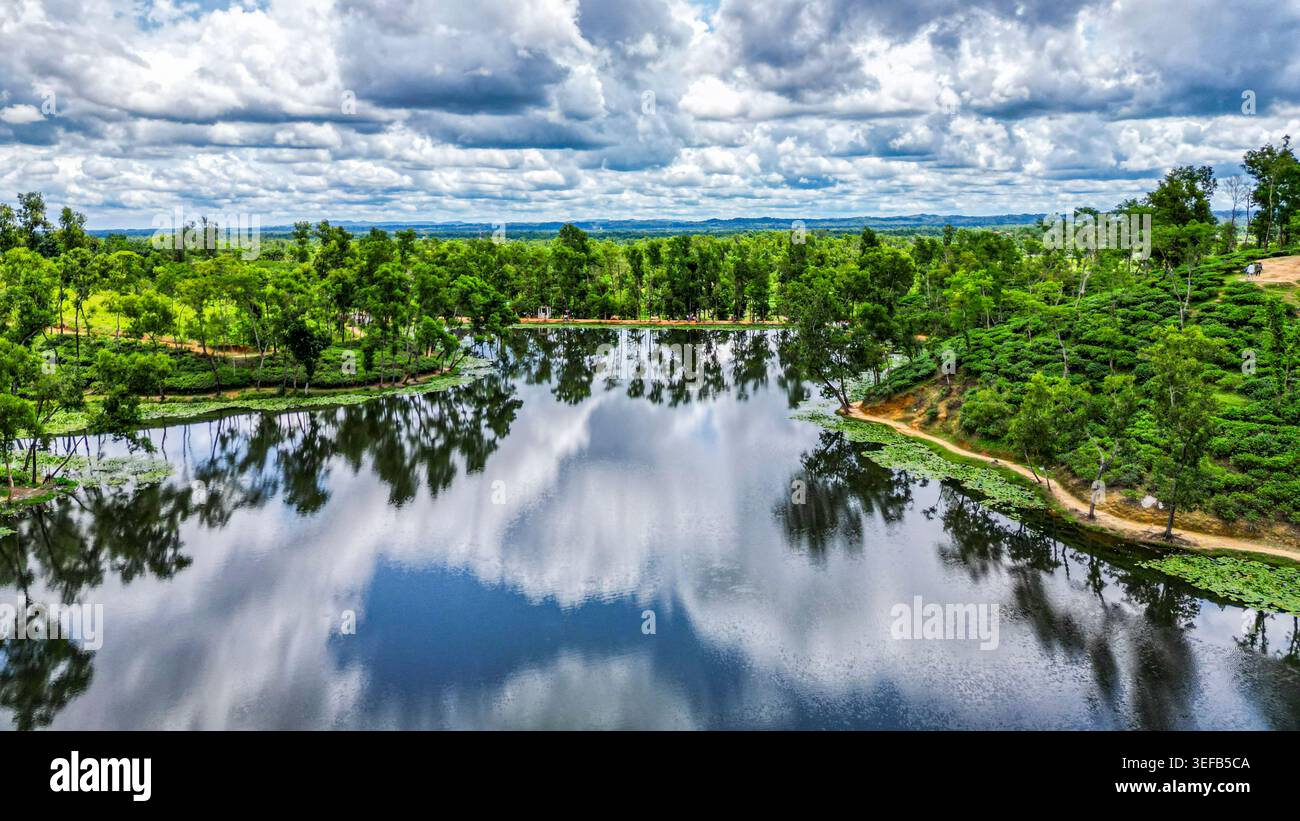 Vista dei giardini del tè e dei corpi idrici nella regione del tè di Sreemangal in Bangladesh con cieli nuvolosi Foto Stock