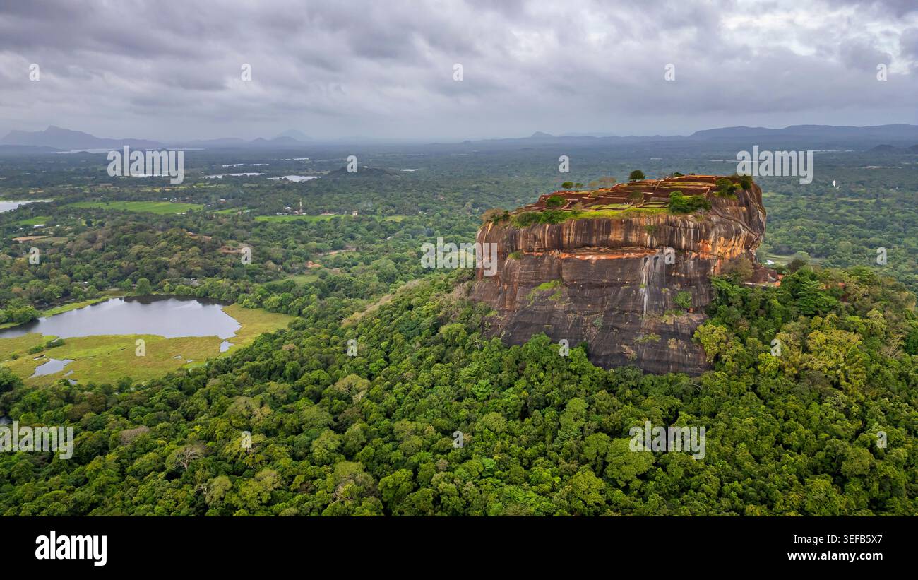 Vista aerea della fortezza rocciosa di Sigiriya nello Sri Lanka circondata da vegetazione lussureggiante e corpi d'acqua Foto Stock