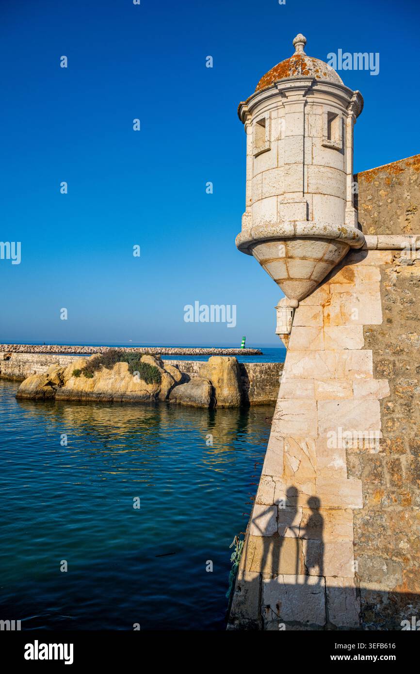Vista dal forte di Ponta da Bandeira che mostra la costa di Lagos con l'ombra di due persone vicino all'acqua Foto Stock