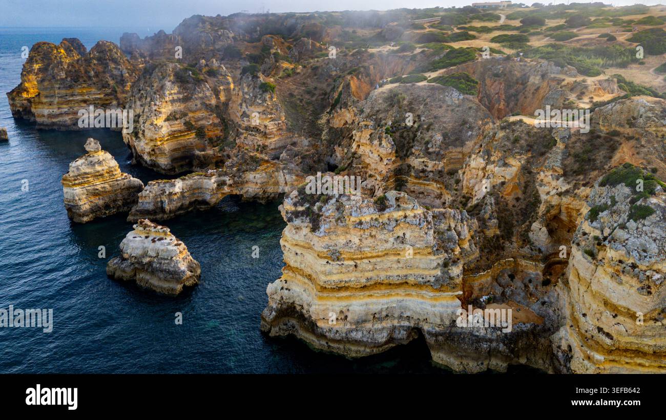 Vista al tramonto delle scogliere sulla spiaggia con onde oceaniche nella regione portoghese dell'Algarve vicino alla città di Lagos Foto Stock