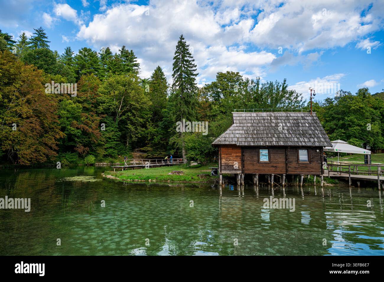 La visita al Parco Nazionale dei Laghi di Plitvice presenta una casa in legno vicino all'acqua sotto il cielo blu in Croazia Foto Stock