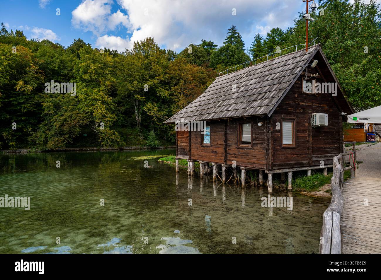 Casa in legno sul lago nel Parco Nazionale dei Laghi di Plitvice in Croazia in una giornata limpida con alberi sullo sfondo Foto Stock