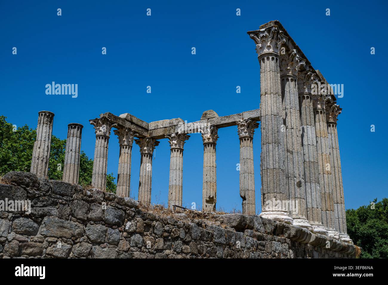 Esplora i resti del tempio romano di Evora in Portogallo, con antiche colonne e cielo blu Foto Stock