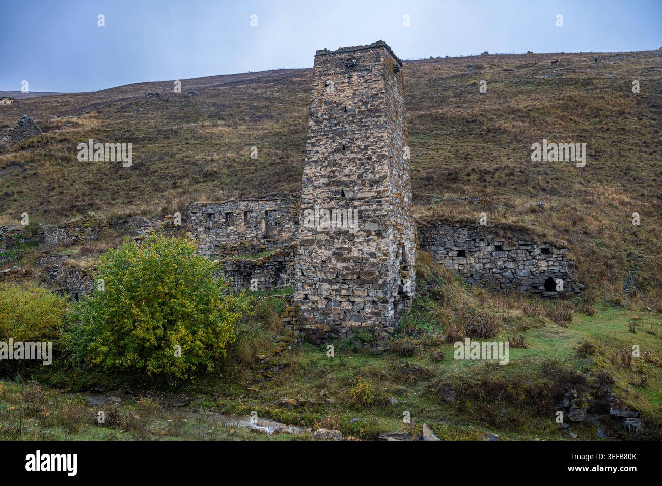 Le rovine del villaggio di Kamunta si trovano da sole nelle montagne del Caucaso dell'Ossezia del Nord, in Russia, sotto un cielo nuvoloso Foto Stock