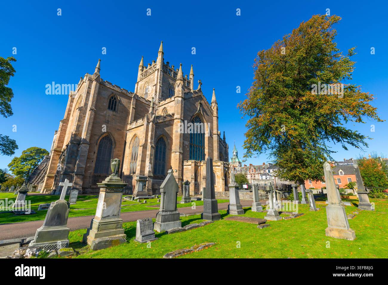 L'abbazia di Dunfermline si erge alta alla luce del sole circondata da lapidi e erba verde a Dunfermline, Regno Unito Foto Stock