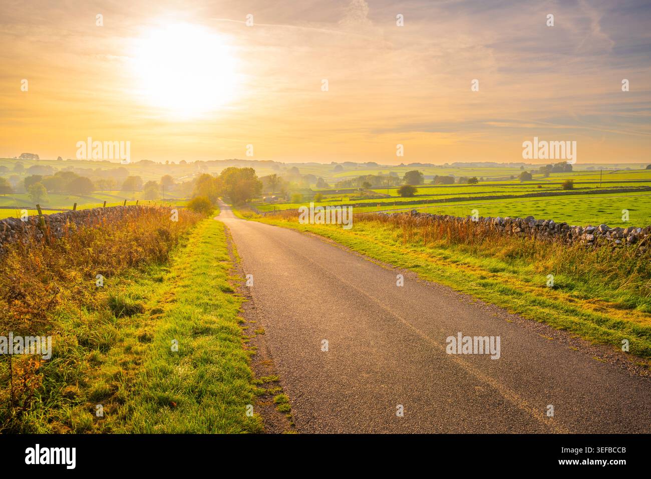 La strada in autunno conduce a Monyash nel Peak District del Derbyshire, in Inghilterra durante il tramonto Foto Stock