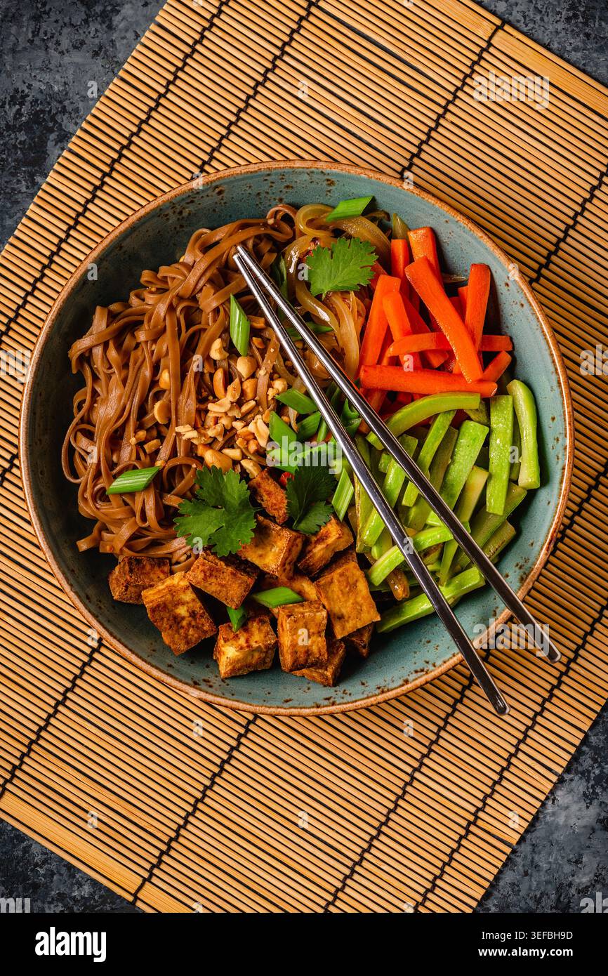 Spaghetti soba con verdure e tofu fritto in un recipiente. Vista dall'alto. Foto Stock