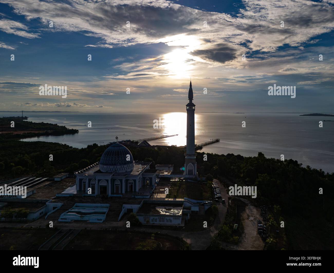 Vista aerea della grande Moschea di Nur Ilahi con il suo alto minareto e la cupola blu che si affaccia sul mare al tramonto Tanjung Pinang, Isole Riau, Indonesia. Foto Stock