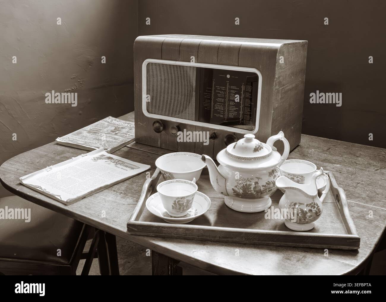 Uno spettacolo domestico vintage con un tradizionale tè bianco in porcellana su un tavolo accanto a una vecchia radio a Blickling Estate, Norfolk, Inghilterra Foto Stock