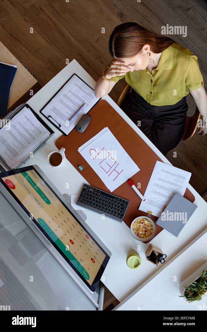 Verticale di donne adulte che si sentono bruciate alla scrivania durante la crisi sul posto di lavoro Foto Stock