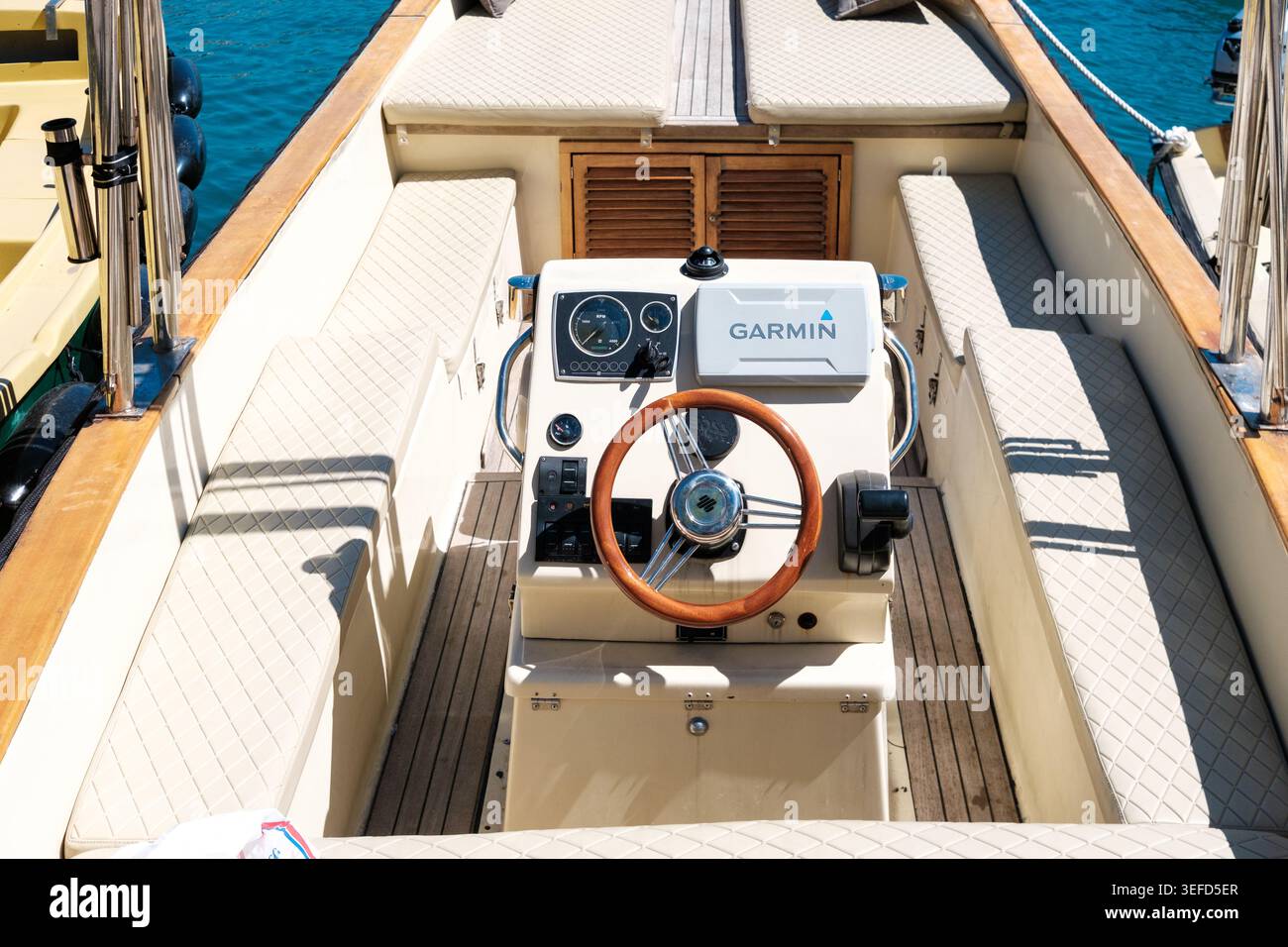 Budva, Montenegro - 28 aprile 2026: Salpa con un sistema GPS Garmin visibile al timone di una piccola barca sulle tranquille acque blu, perfetto per il nav Foto Stock
