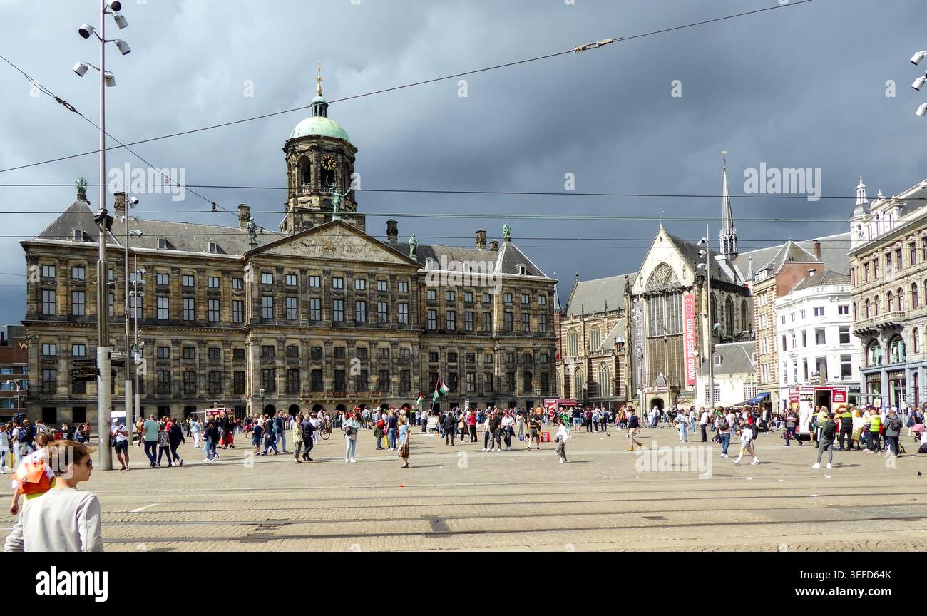 Piazza urbana trafficata con edifici storici sotto un cielo buio ad Amsterdam, che mostra un'atmosfera vivace della città. Foto Stock