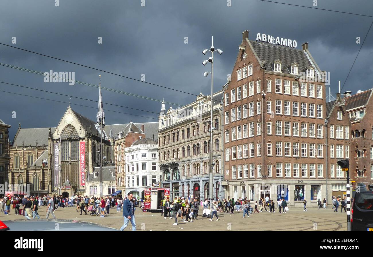 Piazza trafficata dominata da edifici storici sotto nuvole scure ad Amsterdam, Paesi Bassi. Foto Stock
