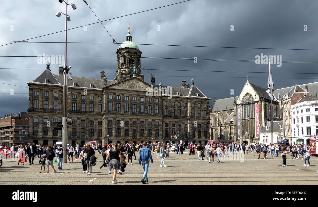 Piazza urbana trafficata con edifici storici sotto un cielo buio ad Amsterdam, che mostra un'atmosfera vivace della città. Foto Stock