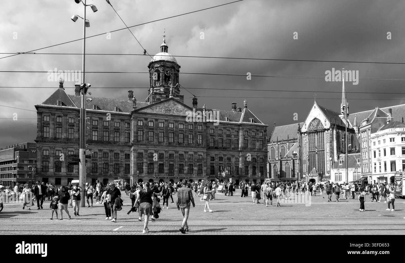 Le folle si riuniscono in una storica piazza di Amsterdam, catturando la vita urbana con tonalità senza tempo di bianco e nero. Foto Stock