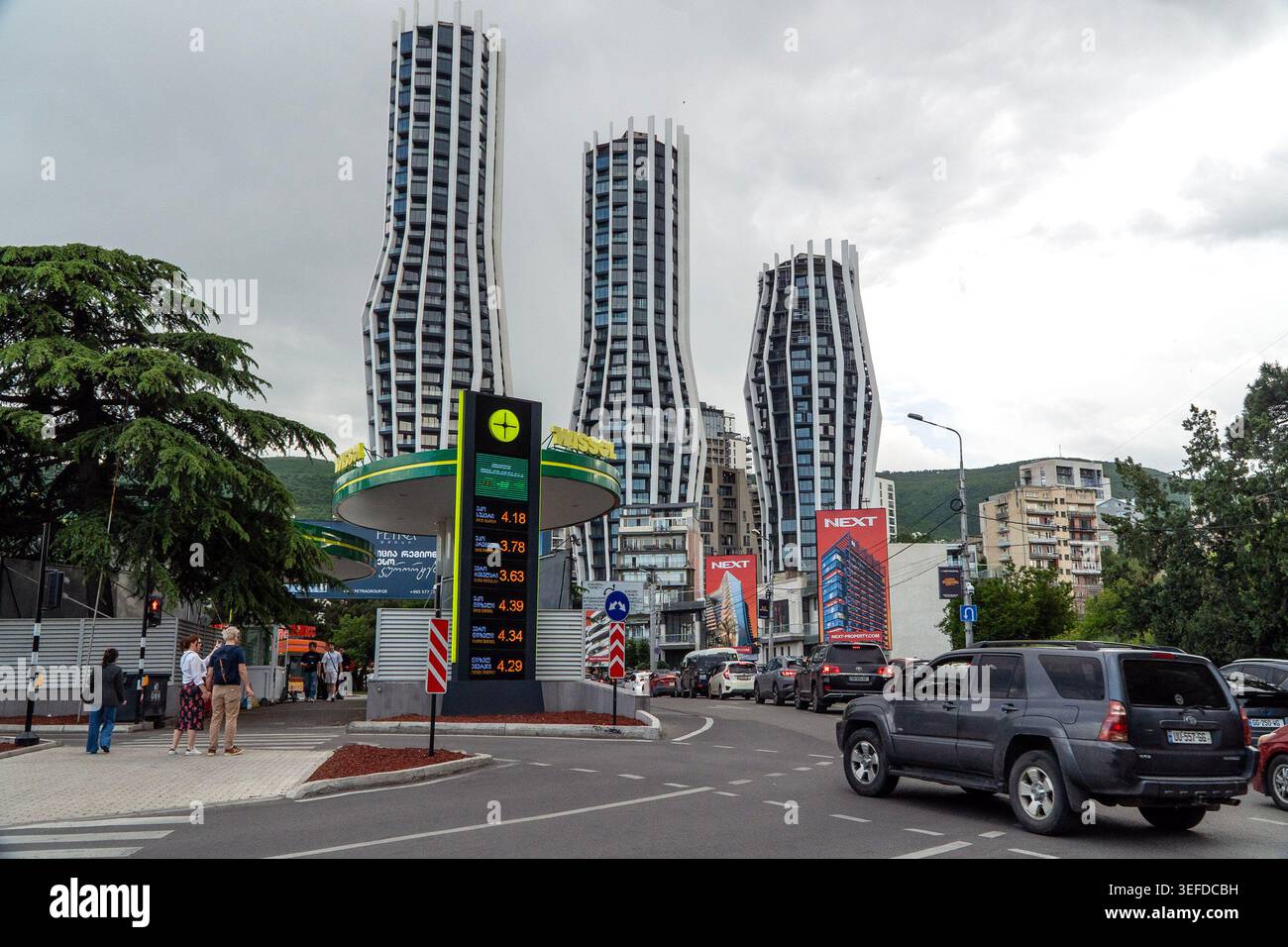 Edifici moderni dal design unico e curvo spiccano in un ambiente urbano, circondato da veicoli e attività di strada. Foto Stock