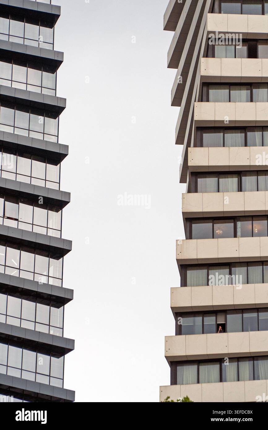 Due moderni grattacieli si ergono alti contro un cielo luminoso, con facciate in vetro e cemento che riflettono la luce. Foto Stock