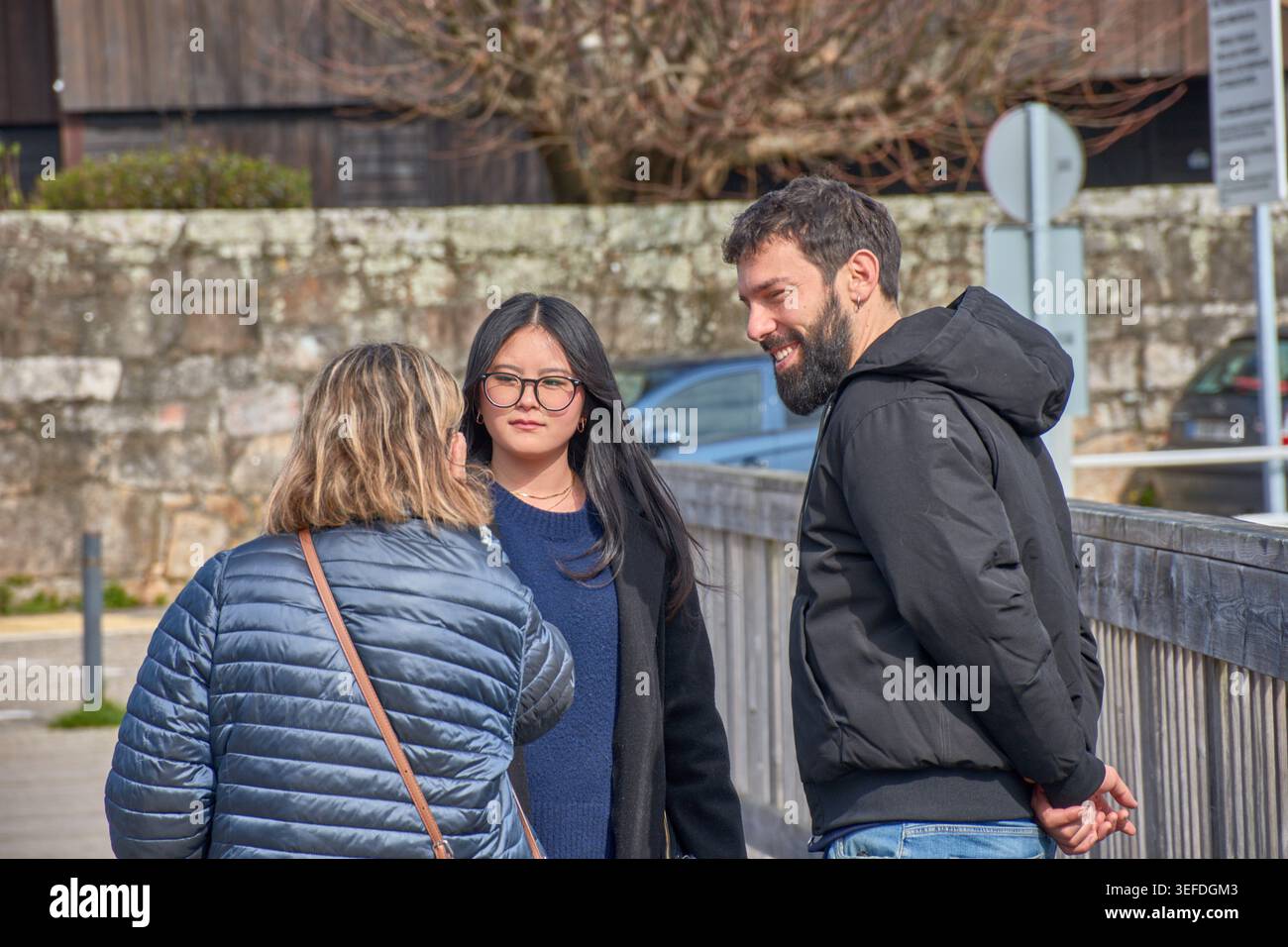Un gruppo di giovani di diverse etnie condivide una conversazione stretta e piacevole, indossando cappotti. Giornate invernali sotto il calore del sole radioso Foto Stock
