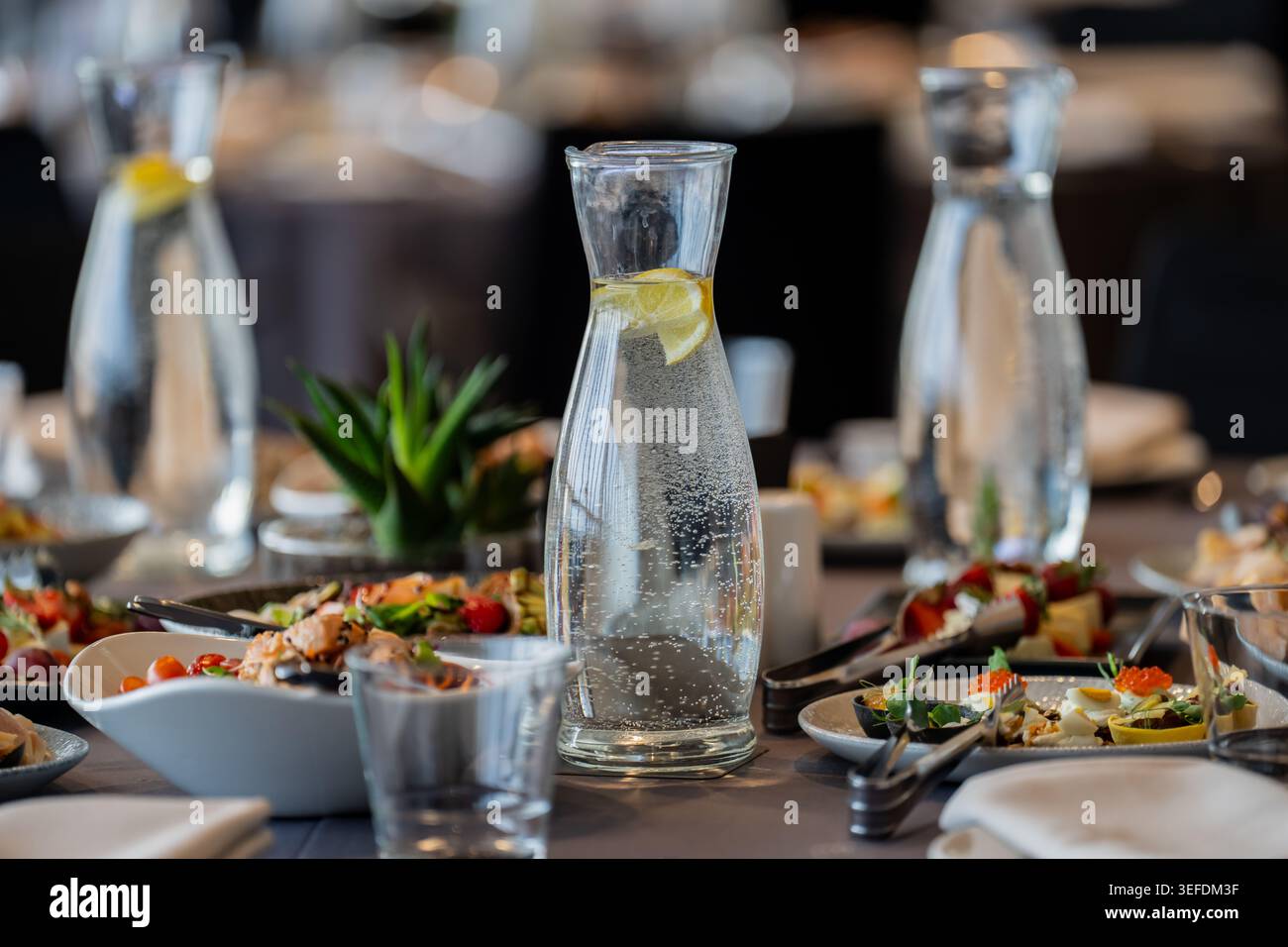 Bevande fredde assortite e antipasti salutari disposti su un tavolo da pranzo per una cerimonia aziendale o un ricevimento di nozze, mettendo in risalto i piatti moderni Foto Stock