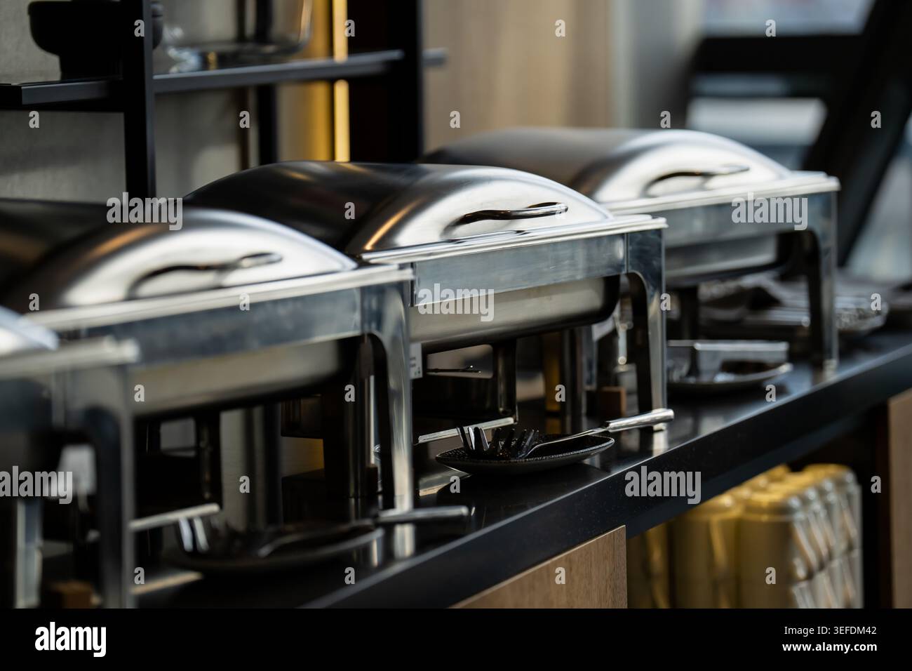 File di piatti professionali in acciaio inox su banco buffet in un ristorante di lusso, che illustrano servizi di catering di alta qualità e hospit Foto Stock
