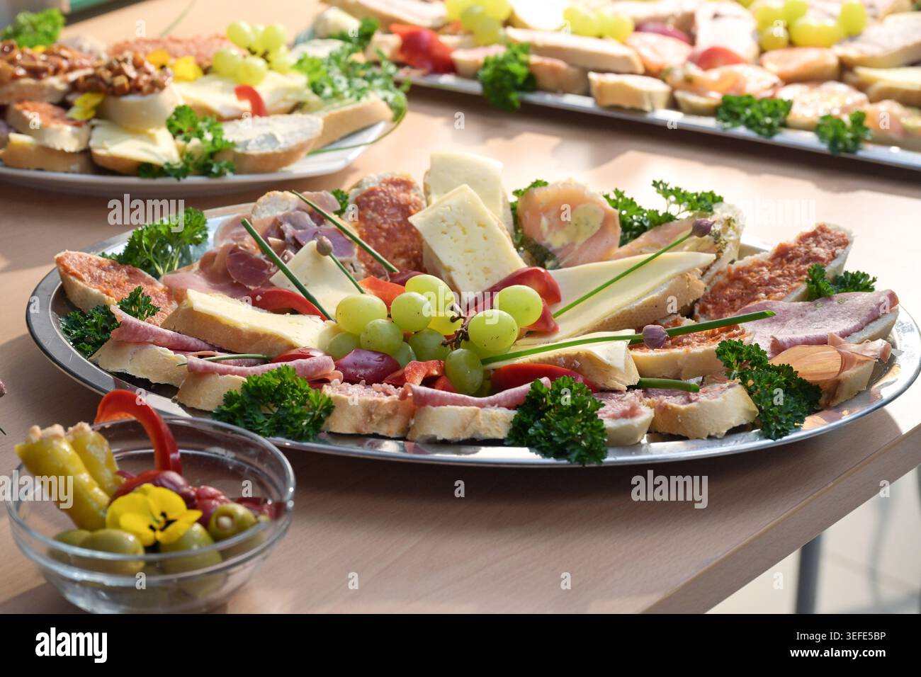 Sandwich assortiti a vista o tartine ricoperti di erbe aromatiche e uva, serviti su piatti grandi, snack per feste a buffet, focalizzazione selezionata Foto Stock