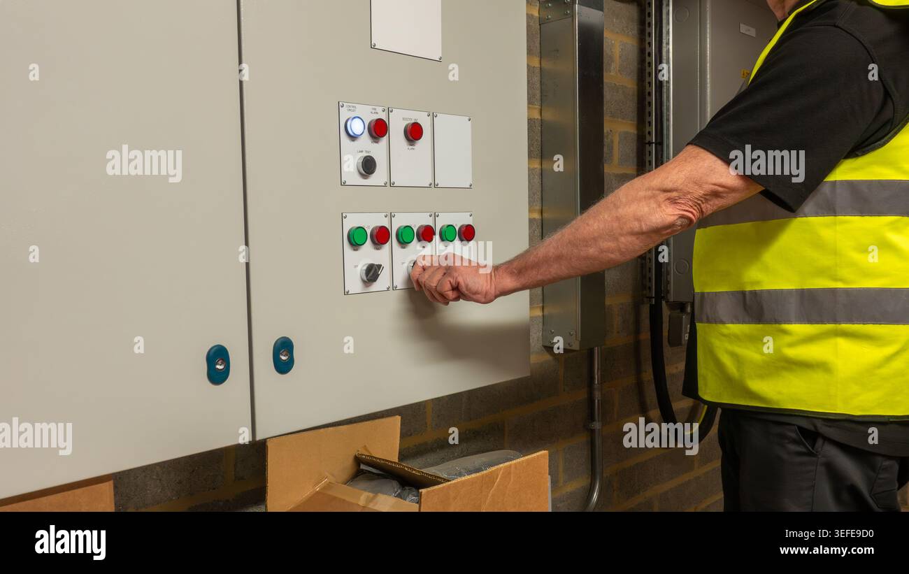 Tecnico dell'aria condizionata e della ventilazione che modifica le impostazioni di funzionamento su un interruttore del pannello di controllo per un'unità di trattamento dell'aria durante l'installazione e la manutenzione HVAC Foto Stock