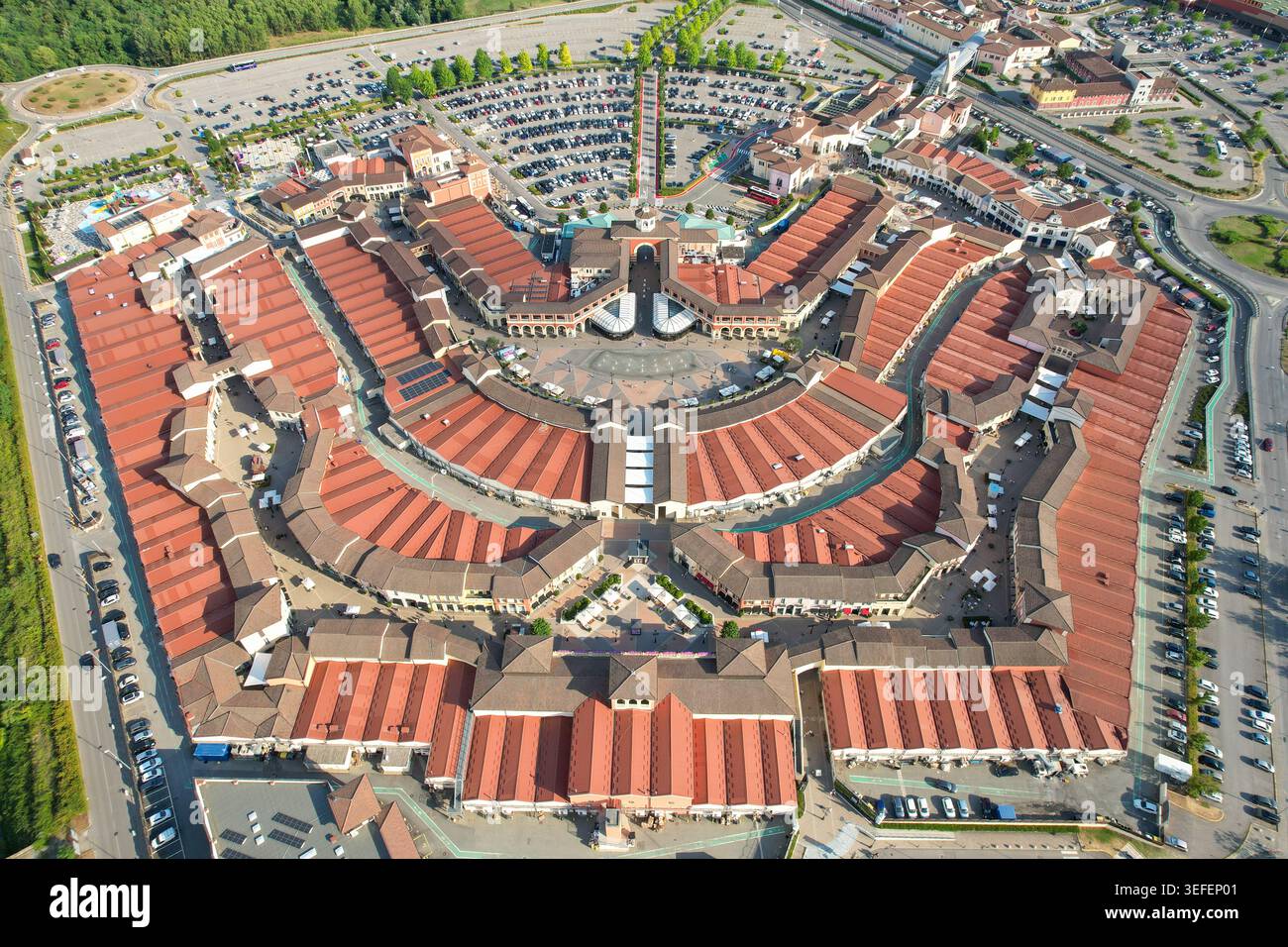 Vista aerea del Designer Outlet Serravalle con la sua caratteristica architettura circolare, i tetti con tegole rosse e le ampie aree di parcheggio Serravalle Scrivia, Foto Stock