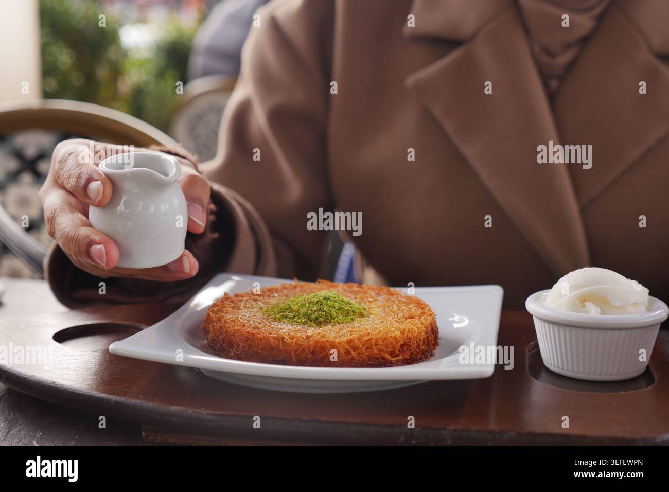 Caldo dessert Kunafa con pistacchio e gelato servito in un intimo tavolo da caffè Foto Stock