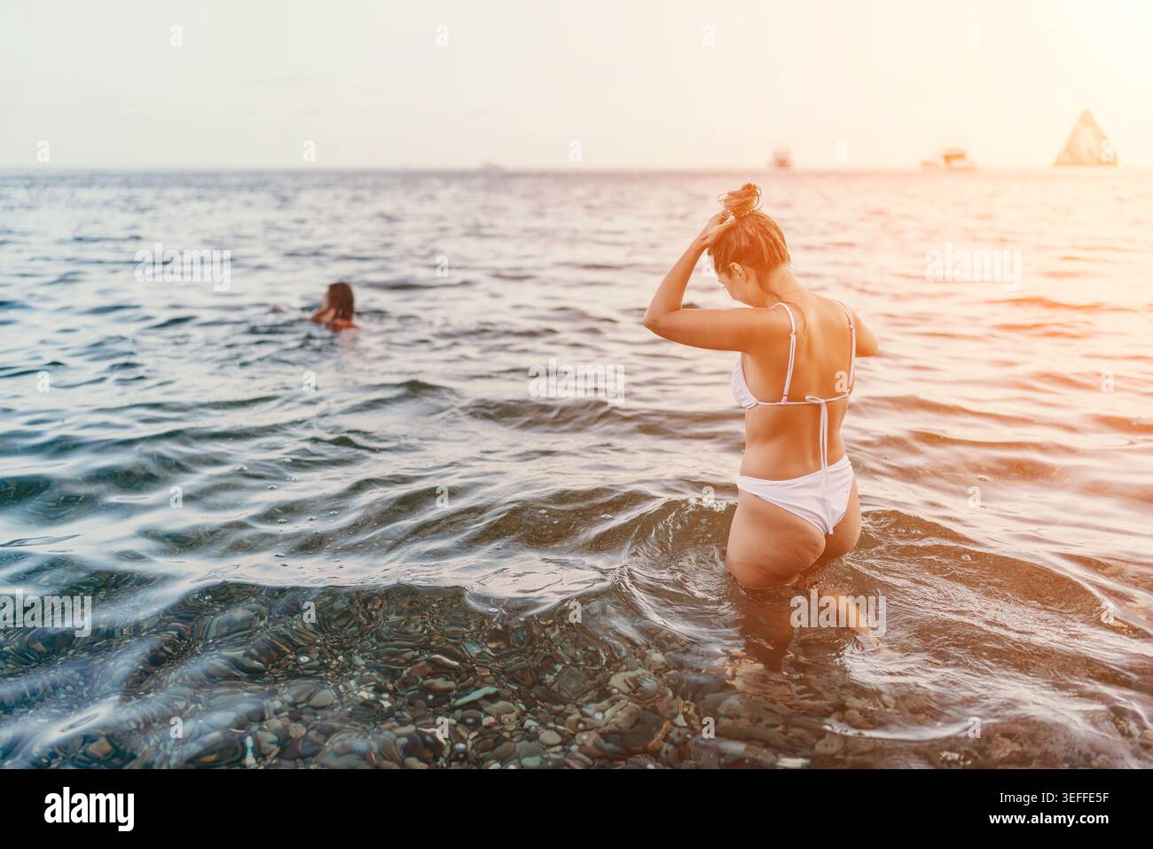 Donna, bikini, mare che si rilassa in acque cristalline al tramonto durante le vacanze estive con spazio fotocopie Foto Stock