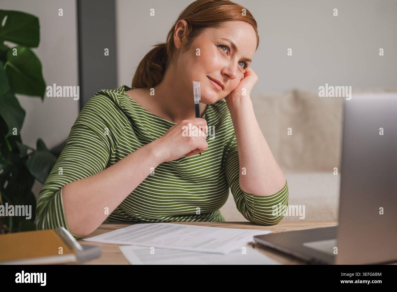 Donna che progetta finanze e pensiero mentre lavora da casa Foto Stock