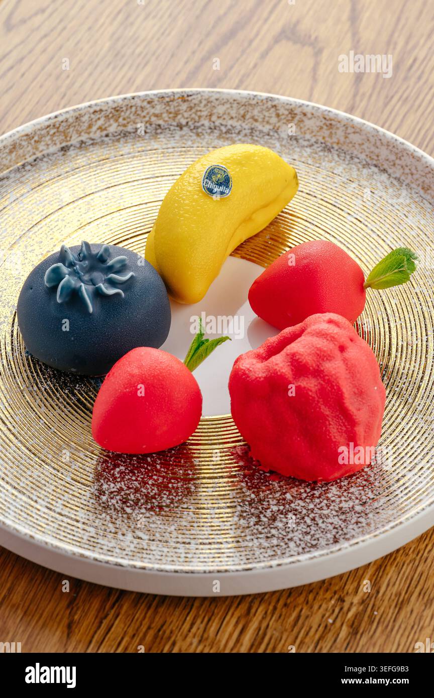 Dessert artistici a forma di frutta su un piatto dorato Foto Stock
