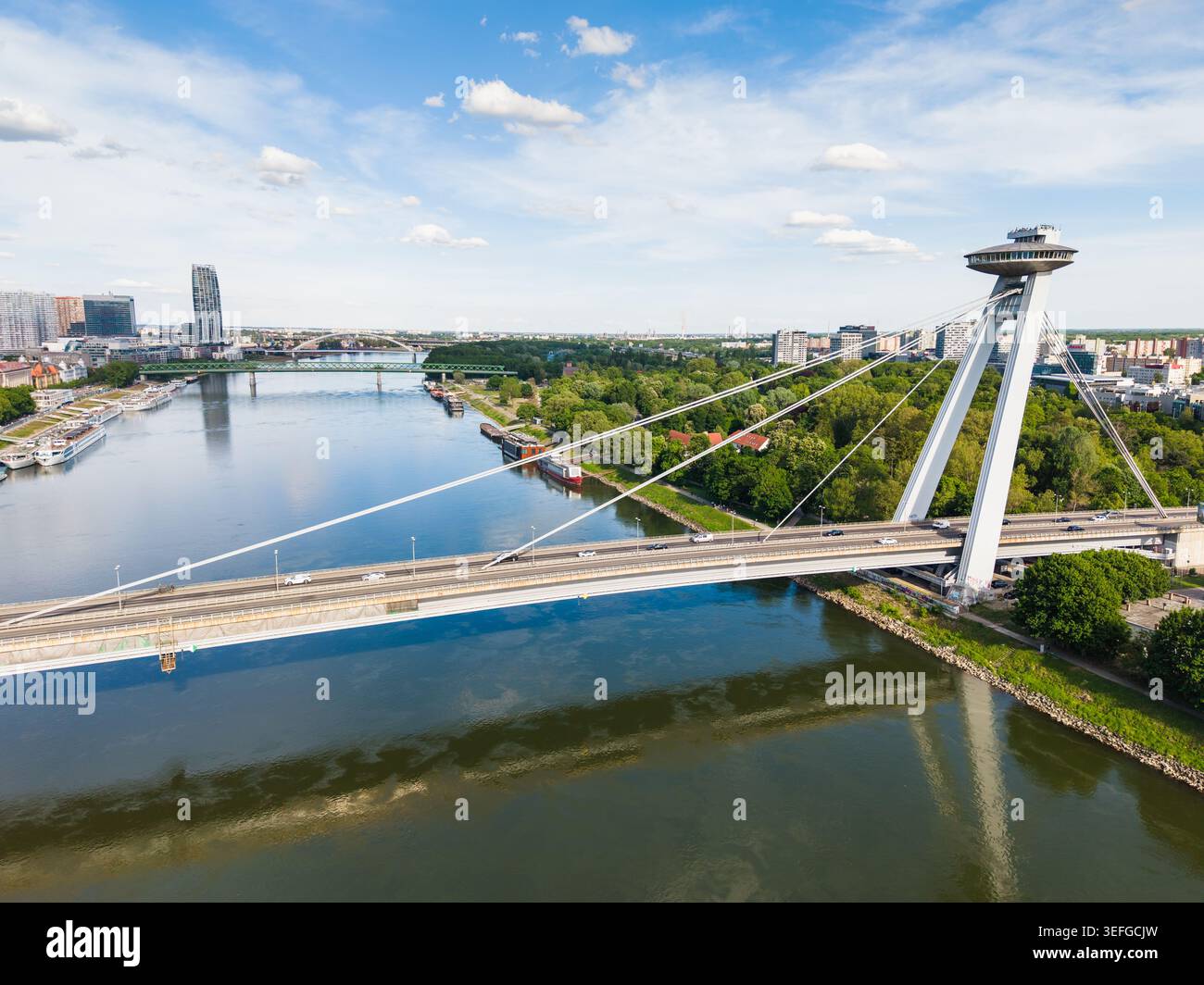 Vista aerea del ponte più SNP con la sua iconica piattaforma di osservazione UFO che attraversa il Danubio sotto un cielo blu a Bratislava, regione di Bratislava, S. Foto Stock