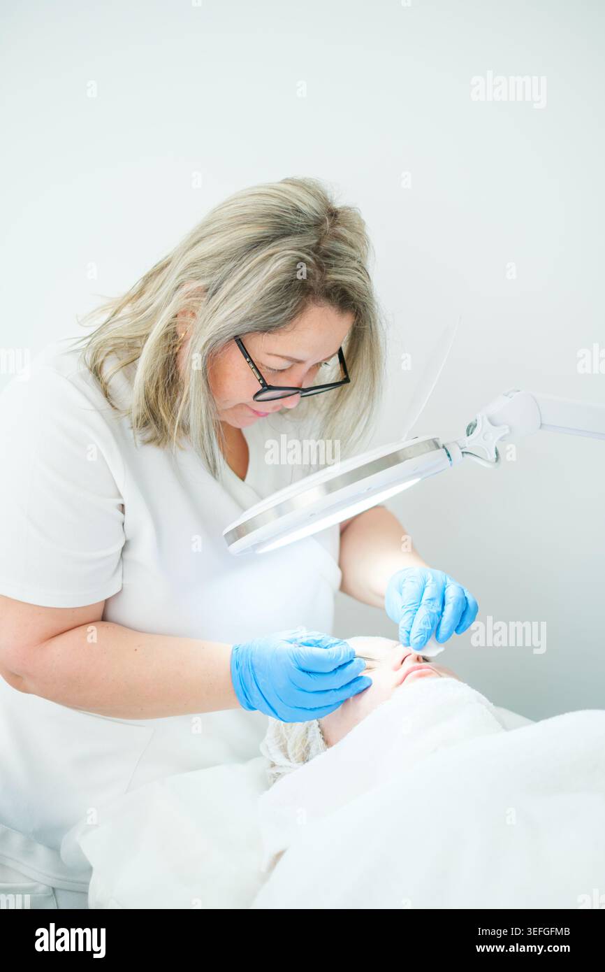 Un estetista cosmetologo utilizza un estrattore di metalli per pulire i pori e rimuovere le imperfezioni per una carnagione più chiara. Foto Stock