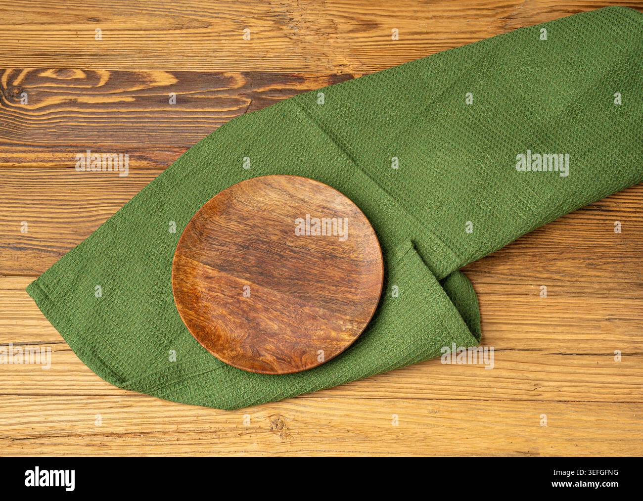 Placca vuota su tavolo in legno vista dall'alto con spazio per copiare il testo, tovagliolo rustico da cucina con tovagliolo verde, placca ecologica su tessuto tovagliolo Foto Stock