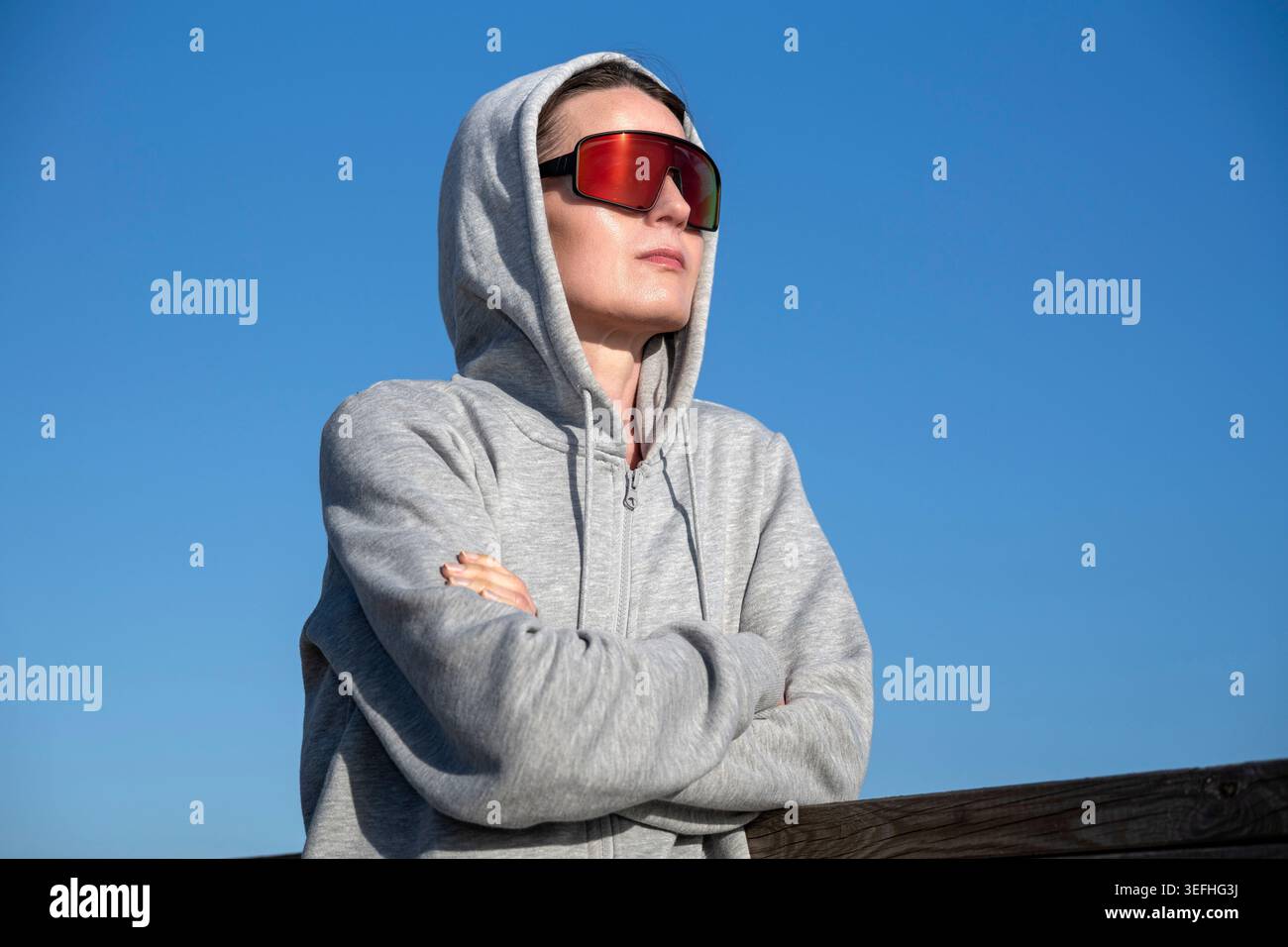 donna che si gode il sole con le braccia incrociate, con gli occhiali da sole Foto Stock