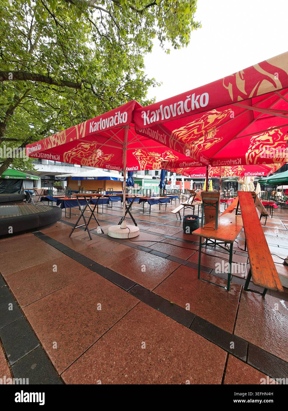 Pforzheim Germania - mai 15, 2026 Beer Exchange. Ampia e tranquilla terrazza con alberi frondosi e ombrello rosso Foto Stock