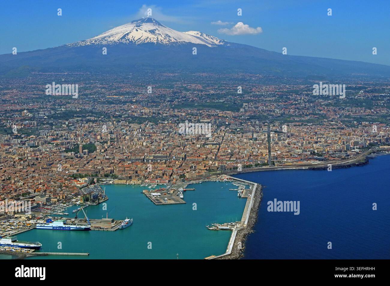 Porto e città di Catania con il Monte Etna innevato sullo sfondo, Sicilia, Italia. Foto Stock