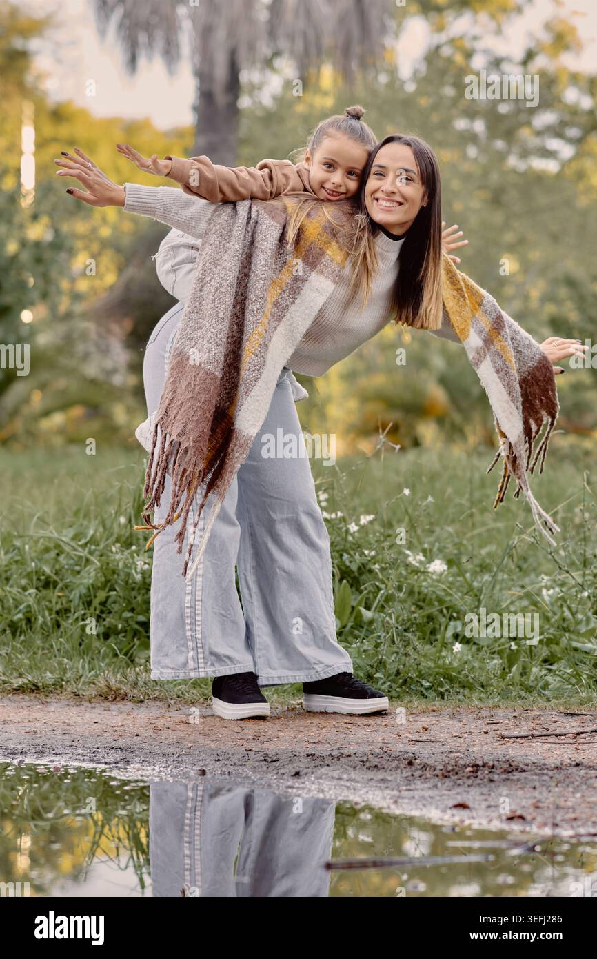 Mamma e figlia si godranno un gioioso momento autunnale, una posa giocosa e una calda luce naturale che creano una potente scena di vita familiare ideale per l'amore, bo Foto Stock