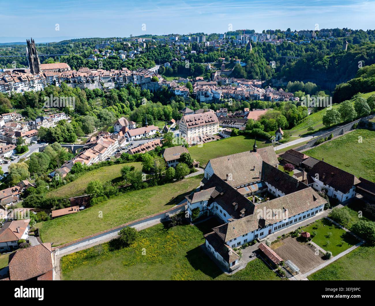 Vista aerea del Monastere de Montorge circondato da prati verdi con lo storico skyline di Friburgo e la Cattedrale di San Nicola sullo sfondo Foto Stock