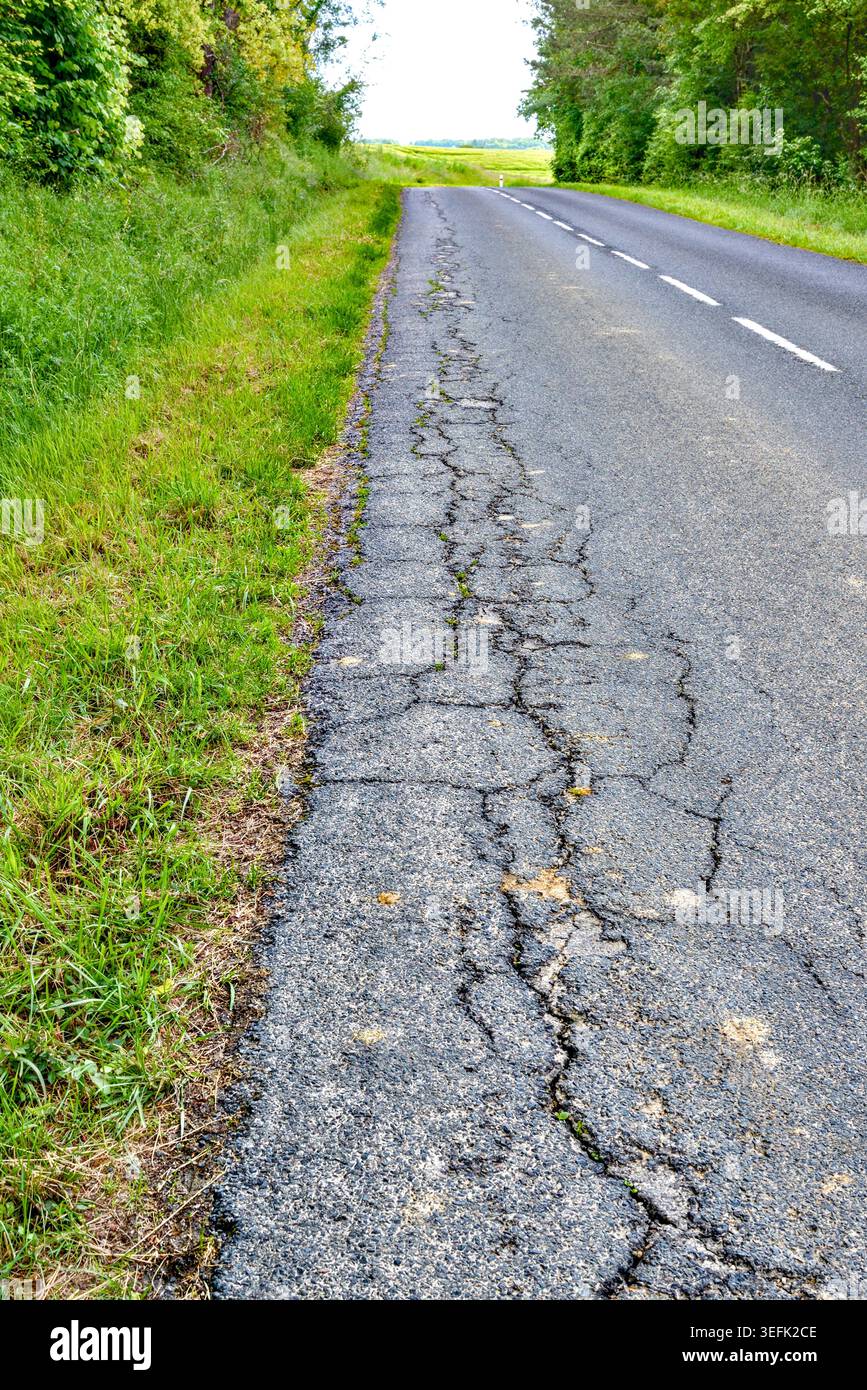 Area di crepe nell'asfalto ai margini della strada di campagna a causa del traffico intenso - Francia centrale. Foto Stock