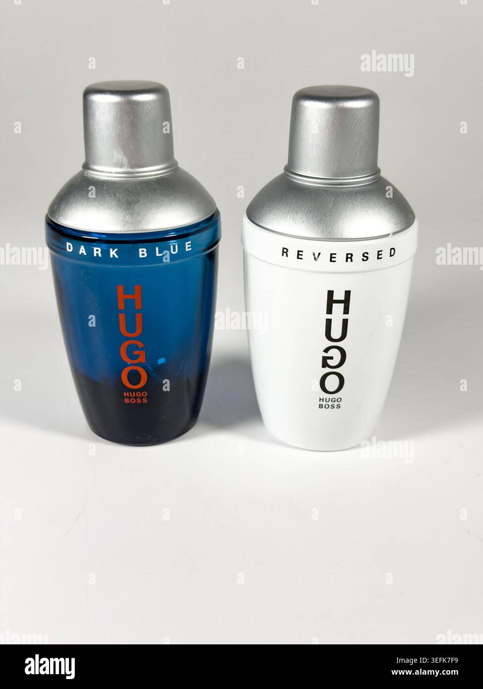 Due bottiglie di fragranza Hugo Boss, tra cui Dark Blue e Reversed Edition, esposte fianco a fianco su uno sfondo grigio chiaro Foto Stock
