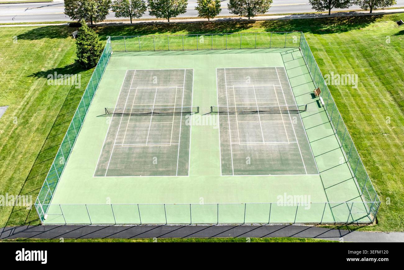 Due campi da baseball si trovano fianco a fianco in un parco verde. Sono vuote e pronte per l'uso nelle giornate di sole. Alberi e una strada sono visibili sullo sfondo. Foto Stock