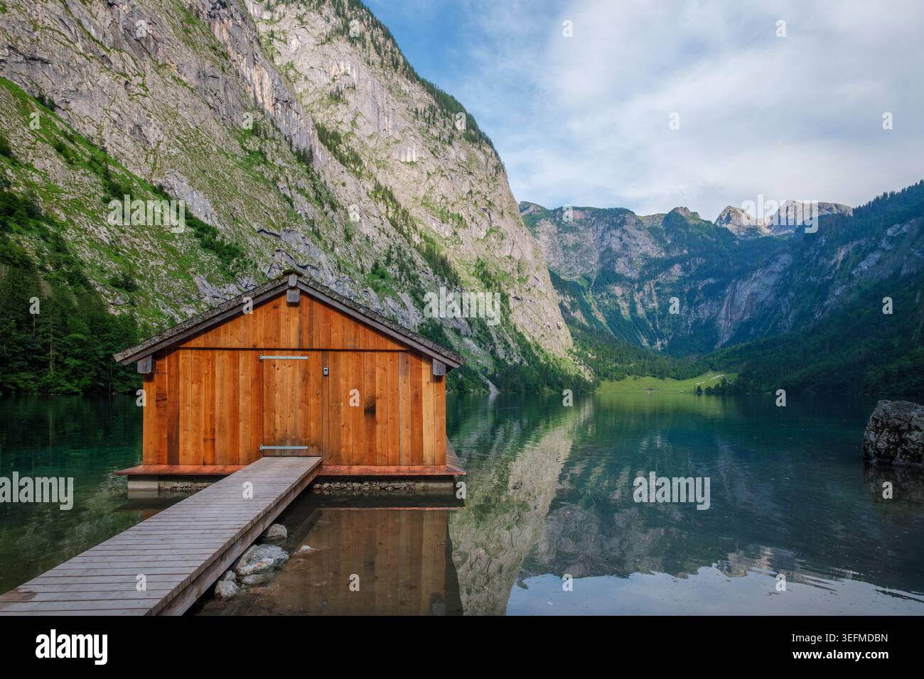 Un solitario capannone di legno si trova sul tranquillo lago Obersee circondato dalle massicce cime calcaree di Berchtesgaden, Germania. Foto Stock