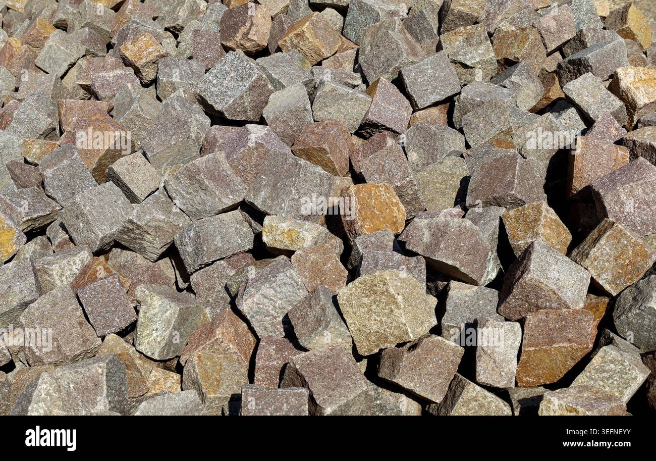 Ampio mucchio di cubetti di porfido pronti per l'uso su marciapiedi o marciapiedi esterni. Materiali da costruzione. Sfondo e trama. Foto Stock