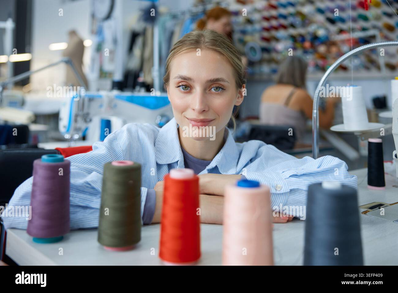 Artigiana circondata da fili colorati e macchine. Foto Stock