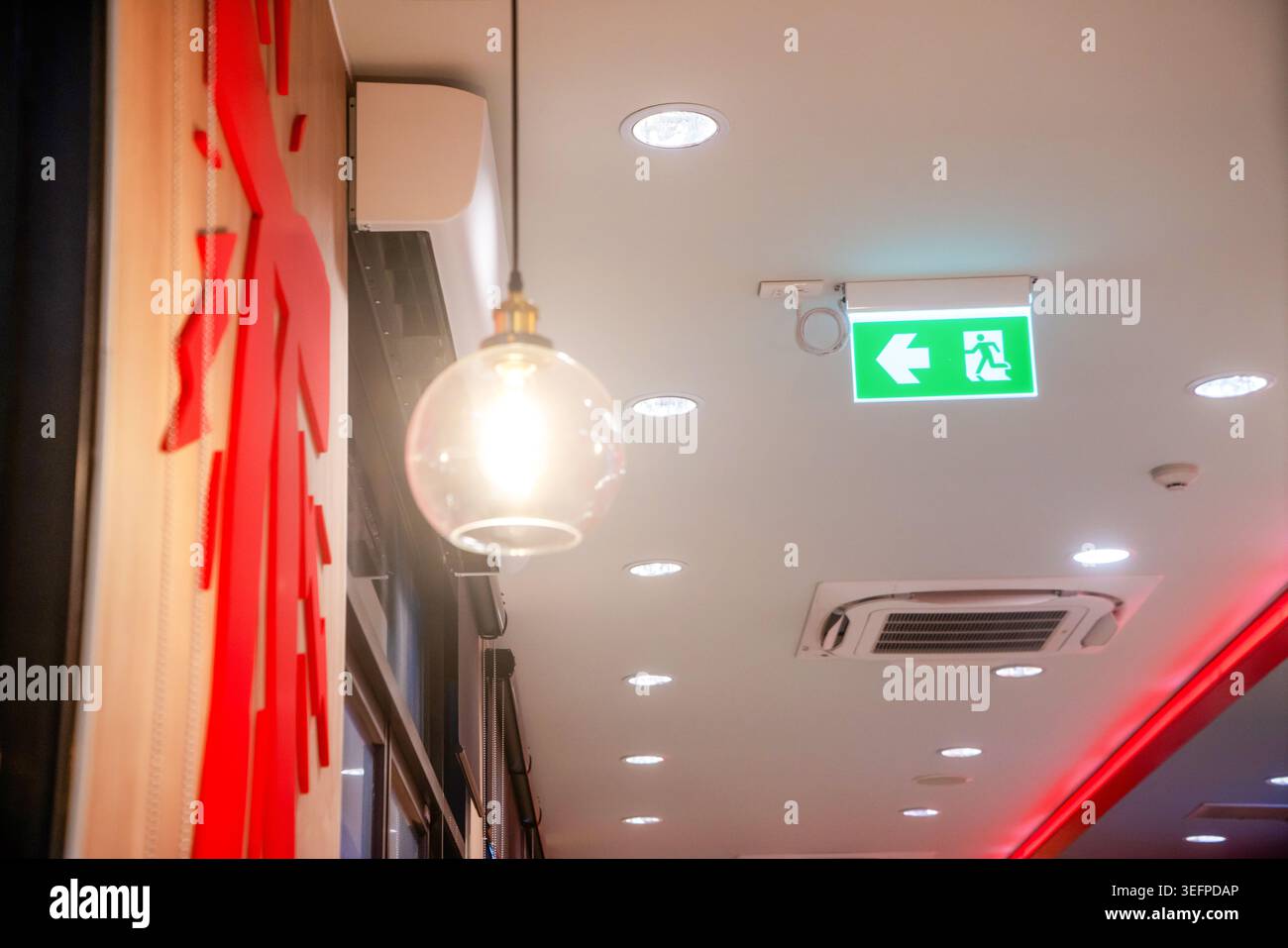 L'immagine mostra un moderno soffitto interno con eleganti sistemi di illuminazione, tra cui una lampada a globo in vetro sospesa e più plafoniere Foto Stock