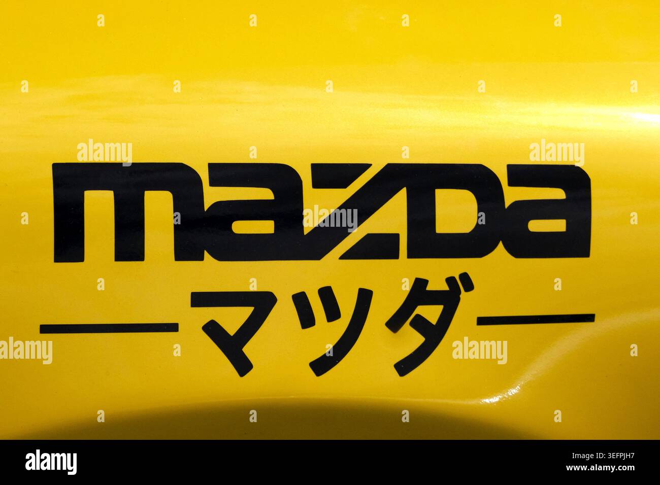 Un adesivo in vinile nero su misura per Mazda con la tipografia classica del logo del marchio inglese abbinata alla sua controparte in script Katakana giapponese. Foto Stock
