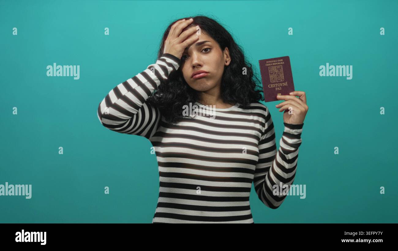 Giovane donna bruna con passaporto ceco con mano sulla fronte in studio sullo sfondo color verde acqua, frustrazione di viaggio. Foto Stock